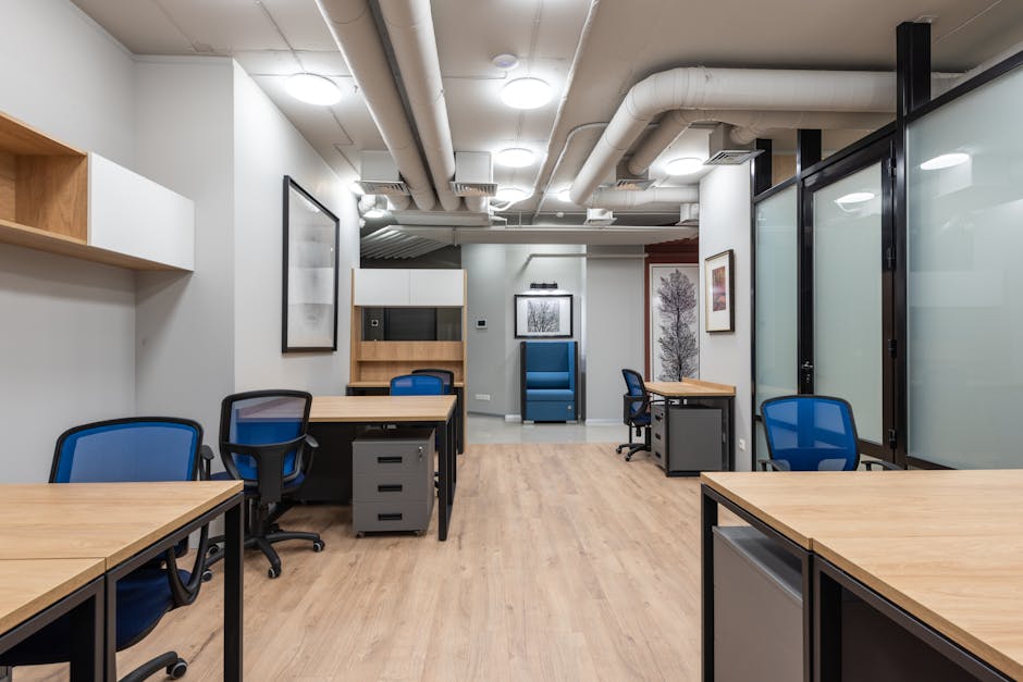 Wooden tables and office chairs placed in modern workplace with bright illumination from ceiling lamps